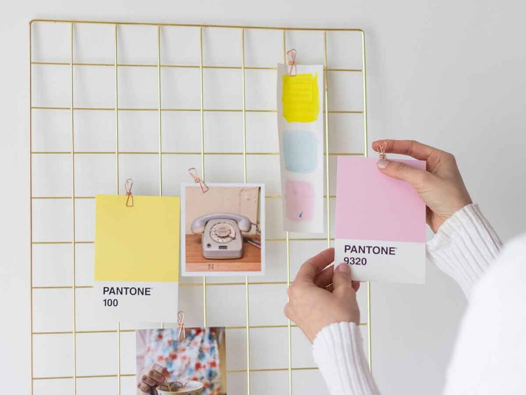 A Person Holding A Paper With A Color Palette Attached To A Wire Board