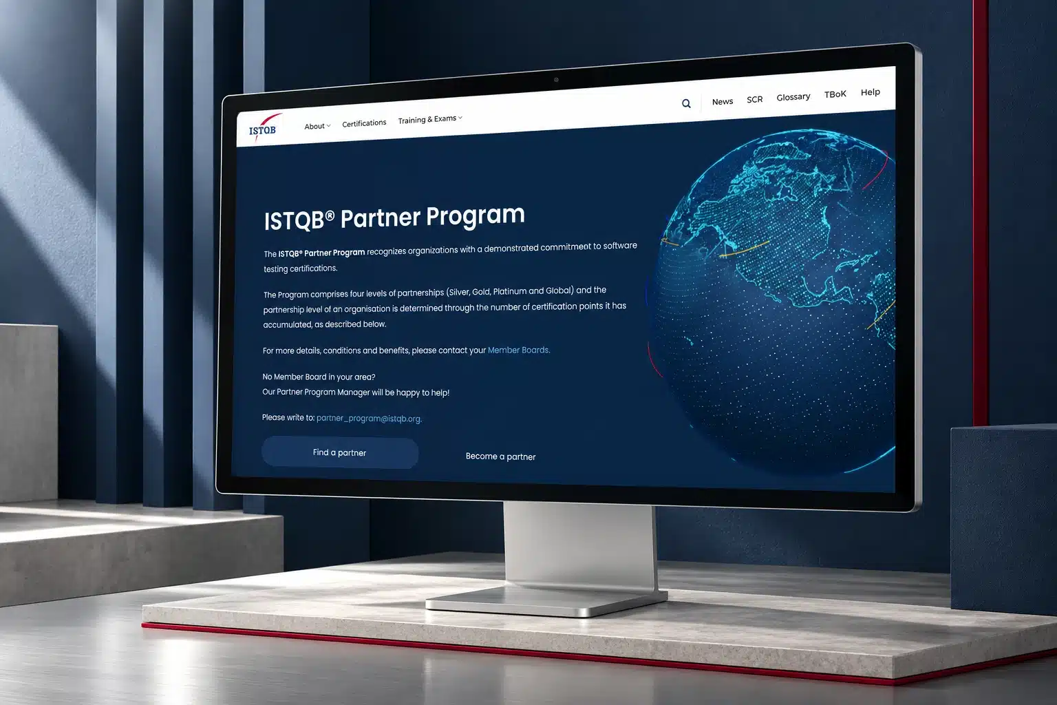 ISTQB Partner Program website on an Apple Studio Display in a navy architectural setting